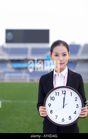 Une femme tenant une grosse horloge Banque D'Images