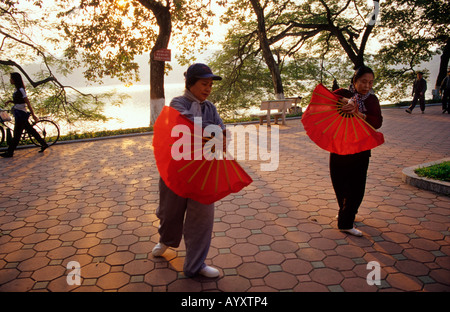 Des femmes matin exercices avec main rouge fans.Lac Hoan Kiem Hanoi Vietnam du Nord Banque D'Images