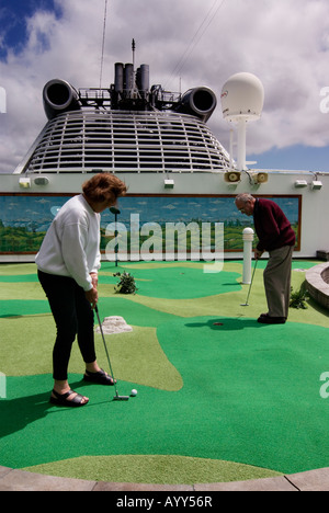 Un couple de personnes âgées jouer au golf sur un bateau de croisière. Banque D'Images