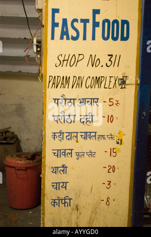 Menu de restauration rapide indien peint à la main sur un mur jaune à Shimla, Himachal Pradesh, Inde, énumérant les plats locaux et les prix en hindi. Banque D'Images