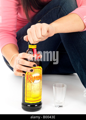 Jeune Adolescente mineurs assis sur le sol face à lui seul causé l'abus d'alcool Boire de l'alcool porte un haut rose et bleu denim Jeans Banque D'Images