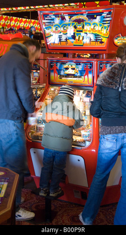 Les parents avec enfant à penny falls machine dans une salle de jeux en bord de mer Banque D'Images