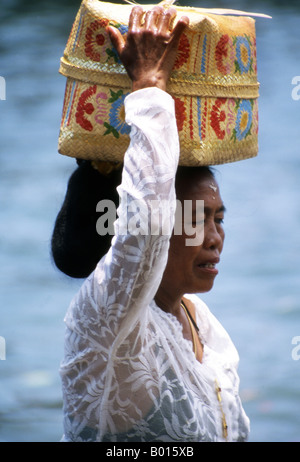 Adorateur balinais portant son panier prier revient de l'autre côté de l'île après la visite de Tanah Lot Temple Bali Indonesia Banque D'Images