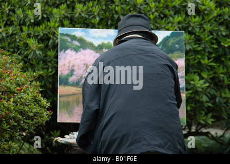 Un peintre met la touche finale à son travail pendant la saison des cerisiers en fleur, parc Shinjuku Gyoen à Tokyo, Japon Banque D'Images