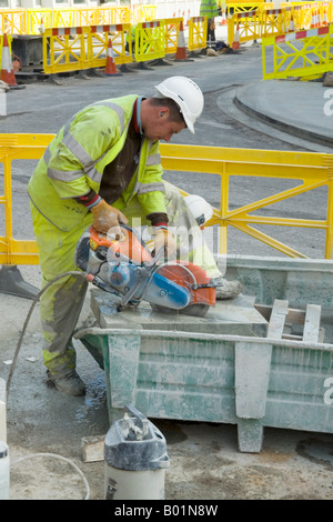 Des hommes au travail, les blocs de coupe voyait toujours en action, la suppression de la poussière à l'aide de l'eau.L'ingénierie routière personnes.La santé et la sécurité.Peinture Banque D'Images