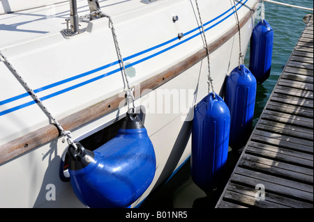 Garde-boue en plastique bleu pendant vers le bas sur le côté du bateau amarré Banque D'Images