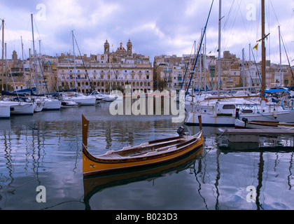 Un bateau traditionnel parmi les bateaux dans Dockyard Creek, Mdina, Malte. Avis de Senglea skyline en arrière-plan. Banque D'Images