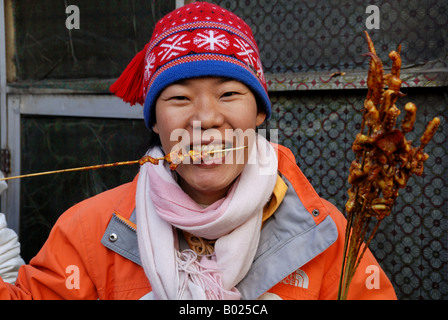 Une femme eating chinese snack-barbecue de poissons-manchon Banque D'Images