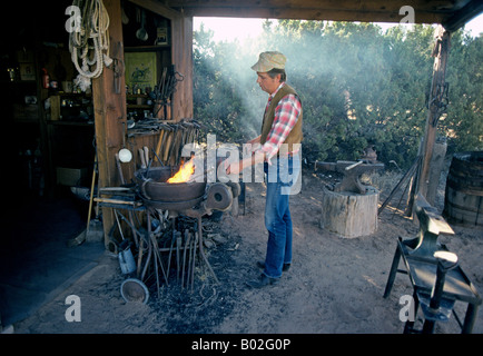 Mark Simmons forgeron fer à repasser chauffe met en œuvre dans sa forge, près de Santa Fe New Mexico Banque D'Images