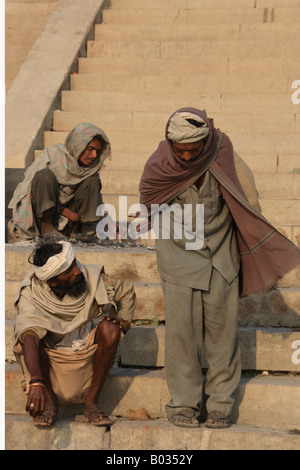 2 Hommes Indiens parler tandis qu'un troisième tend un incendie sur les ghats de Varanasi. Banque D'Images