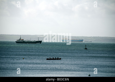 Silhouette de coureurs de bateau Gig avec les grands cargos en arrière-plan, St Mawes, Cornouailles Banque D'Images