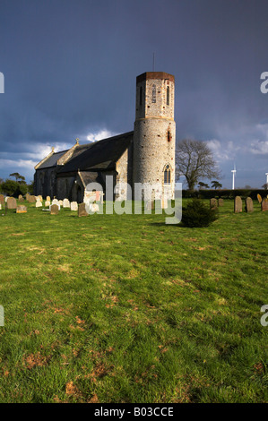 Église à Winterton sur mer avec les éoliennes modernes dans la distance sur un jour de tempête dans le Norfolk. Banque D'Images