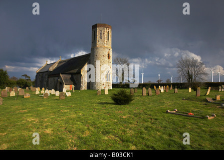 Église à Winterton sur mer avec les éoliennes modernes dans la distance sur un jour de tempête dans le Norfolk. Banque D'Images