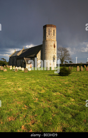 Église à Winterton sur mer avec les éoliennes modernes dans la distance sur un jour de tempête dans le Norfolk. Banque D'Images