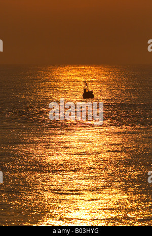 Bateau de pêche au crabe et au lever du soleil sur la côte de Norfolk à Cromer silhouetté contre un merveilleux lever du soleil Banque D'Images