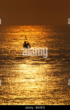 Bateau de pêche au crabe et au lever du soleil sur la côte de Norfolk à Cromer silhouetté contre un merveilleux lever du soleil Banque D'Images