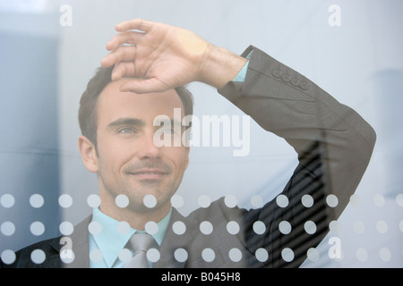 Businessman looking through window Banque D'Images