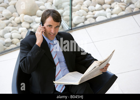 Businessman with newspaper et téléphone Banque D'Images