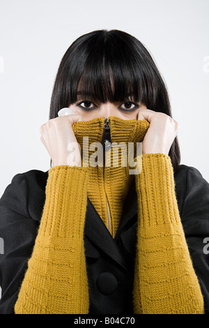 Femme japonais peering over sweater Banque D'Images
