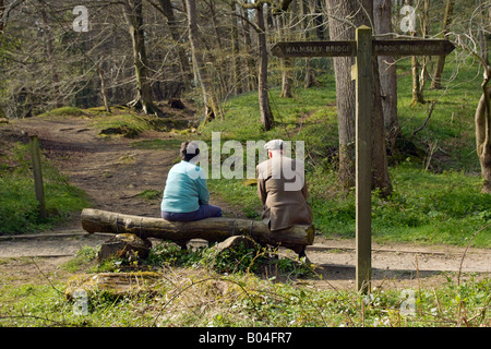 Les marcheurs se reposant sur un banc sous un panneau. Banque D'Images