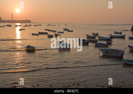 Petits bateaux de pêche ancrés à Playa de la Caleta au coucher du soleil dans la ville de Cadix, Province de Cadiz, Costa de la Luz, Andalousie Banque D'Images