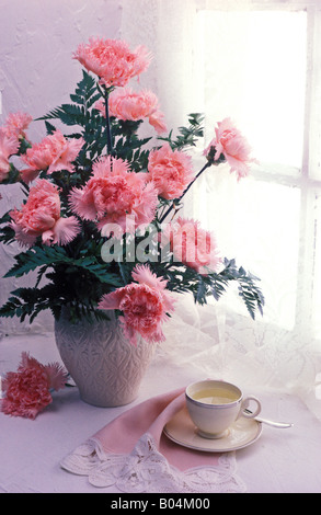 Oeillets roses dans un vase dans la fenêtre Banque D'Images