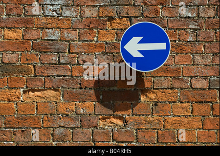 Le sens de la flèche bleu signe sur un vieux mur de briques. UK Banque D'Images