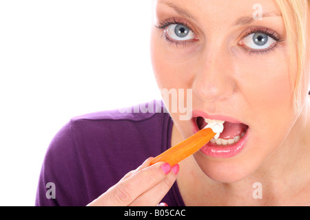 Young Woman Eating Carrot avec modèle Dip publié Banque D'Images