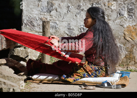 Une femme tribal utilise un métier à l'aide d'un chiffon rouge dans GYASUMDO VILLAGE près de Manang sur le circuit de l'ANNAPURNA NÉPAL HIMALAYA Banque D'Images