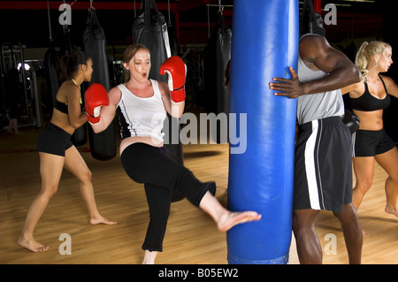 Femme botter un sac lourd lors d'un kick boxing classe dans un MMA gym Banque D'Images