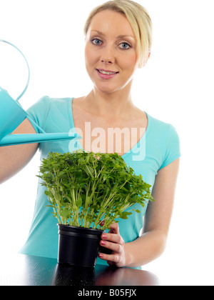 Jeune femme d'arroser un pot de fines herbes prêts à prendre et faire cuire avec un bidon isolé sur un fond blanc et Clipping Path Banque D'Images