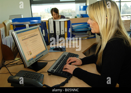 Le personnel dans un bureau en espace ouvert à une association de logement travailler sur l'ordinateur Banque D'Images