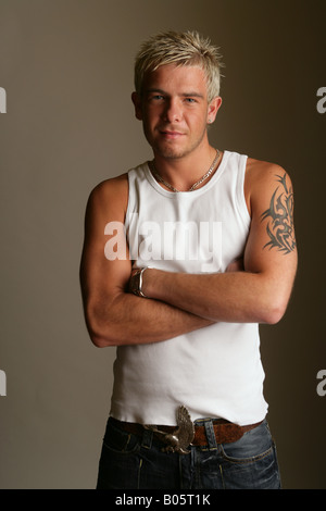 Jeune homme posing in studio with arms crossed Banque D'Images