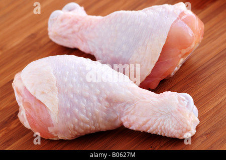 Pilons de poulet crus sur une planche en bois Banque D'Images