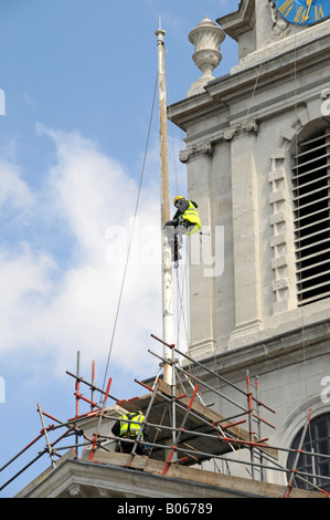 Workman suspendu autour du poteau du drapeau réalisant des travaux d'entretien pendant la restauration de St Martin dans l'église Fields Londres Angleterre Royaume-Uni Banque D'Images