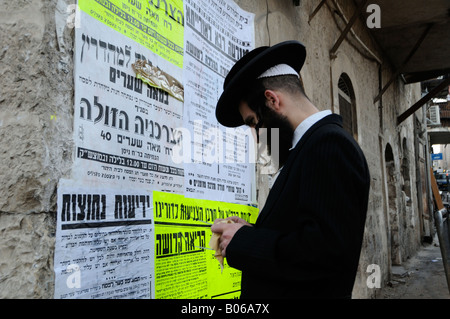 Orthodoxe Jew lit des affiches grand format de Pashkvilim qui servent d'annonces communautaires dans le quartier de Mea Shearim, une enclave ultra-orthodoxe en Occident Banque D'Images