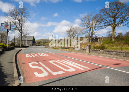 L'Araf rouge bilingue signe la sécurité routière lente peint sur A5 autoroute route avant un virage. Cerrigydrudion au nord du Pays de Galles Royaume-uni Grande-Bretagne Banque D'Images