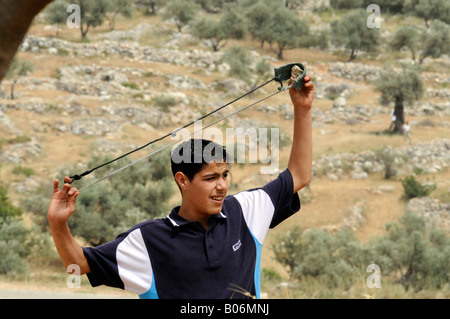 Un enfant palestinien le tournage d'un sling shot au cours d'une manifestation contre le mur et l'occupation dans le village de Bil'in, Palestine. Banque D'Images