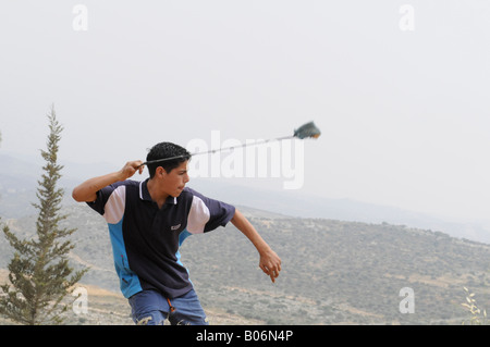 Un enfant palestinien le tournage d'un sling shot au cours d'une manifestation contre le mur et l'occupation dans le village de Bil'in, Palestine. Banque D'Images