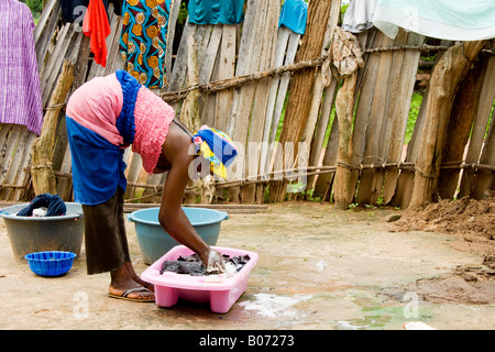 Jeune femme gambienne à laver les vêtements dans le village composé, la Gambie, Afrique de l'Ouest Banque D'Images