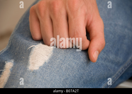 Vue rapprochée de jeans en denim bleu déchiré présentant deux déchirures verticales distinctes ou des écailles vieillies, exposant les fils horizontaux blancs Banque D'Images