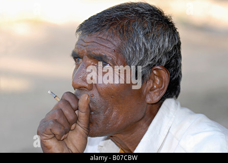 Gros plan d'un homme tribal de Bhil fumant un bidi fumeur, une cigarette artisanale indienne faite de feuilles de tabac. Visages ruraux de l'Inde Banque D'Images