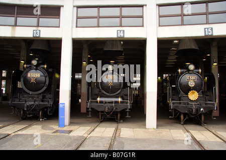 Trois locomotives japonaises d'époque sur des voies dans le hangar de locomotives du hangar de trains du musée de locomotives de courant Umekoji à Kyoto, au Japon. Banque D'Images