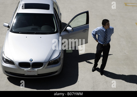Homme debout à côté de son BMW 528 avec porte ouverte Banque D'Images