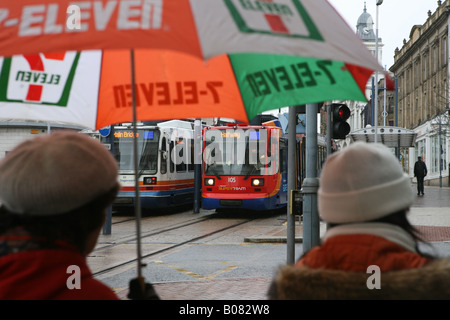 Les piétons à certains des tramways du centre-ville de Sheffield, tenant un parapluie Banque D'Images