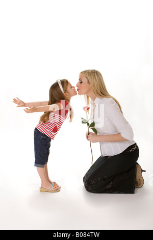 Petite fille de cinq ans se pencher en avant pour donner un baiser de la mère. Fond blanc Banque D'Images