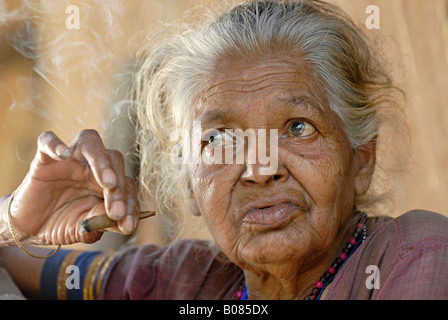 Libre d'une vieille femme fumant bidi, une cigarette à la main indienne faite de feuilles de tabac ou beedi. Tribu Warli, Thane, Inde Banque D'Images