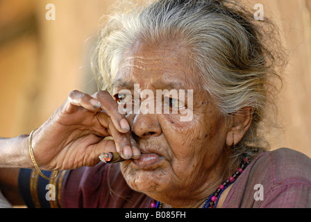 Gros plan d'une vieille femme fumant du bidi, une cigarette artisanale indienne faite de tabac ou de feuilles de beedi. Tribu Warli, Thane, Inde. Visages ruraux de l'Inde Banque D'Images