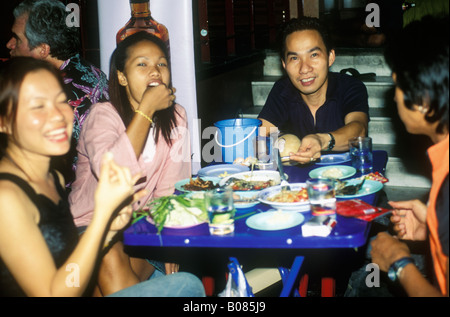 Jeune thaïlandaise aux personnes bénéficiant d'un repas sur la route Sukhumvit Bangkok la nuit Banque D'Images