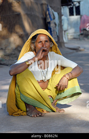 Vieille Femme tribal, un Indien bidi fumeurs de cigarettes à la main du tabac ou beedi feuilles. Tribu Bhil Banque D'Images